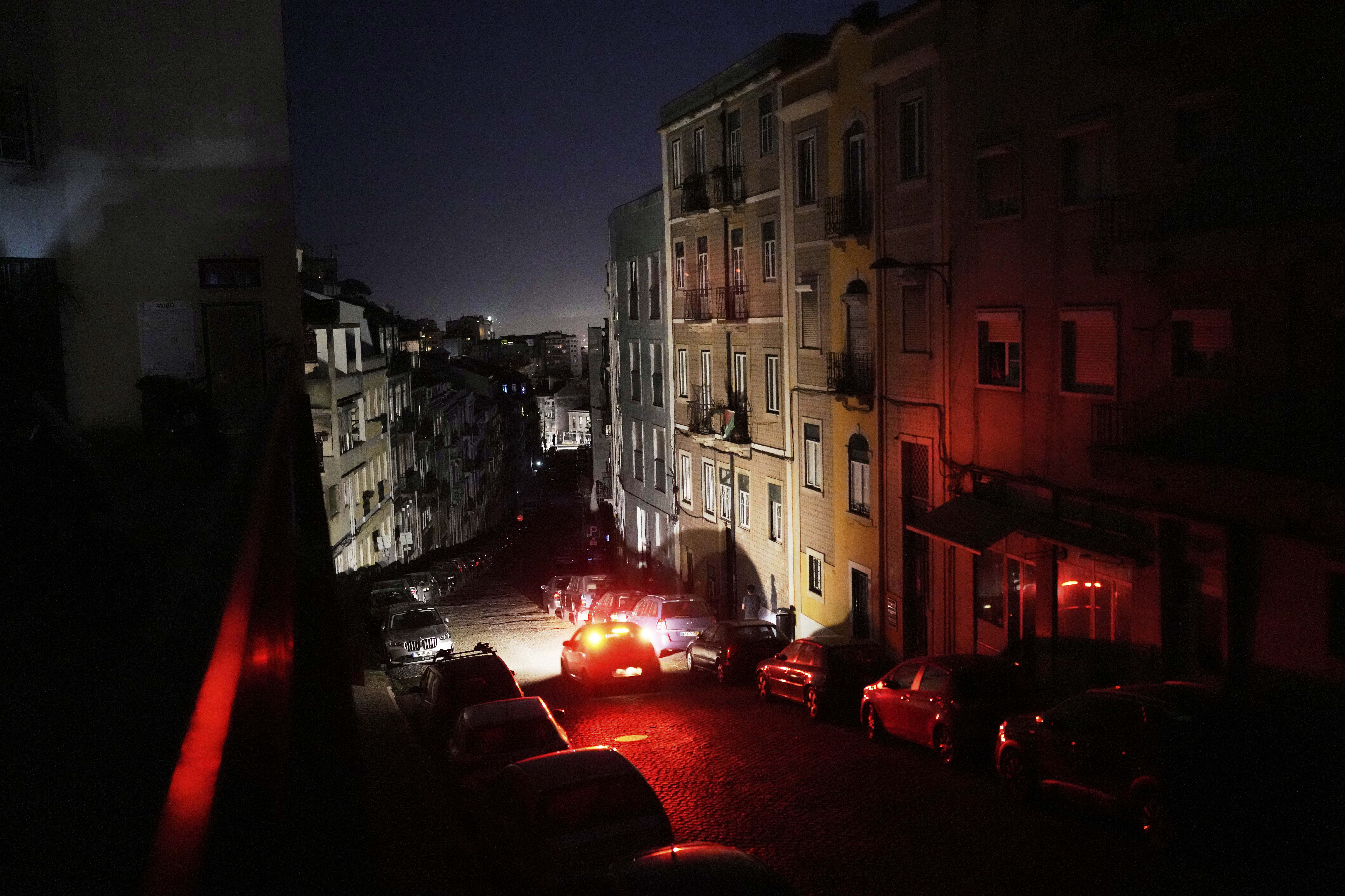 Cars parked on a dark Lisbon street during a power outage.